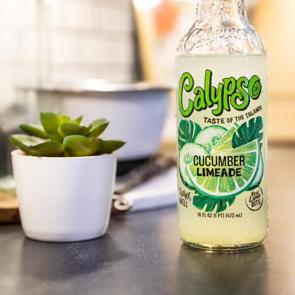 A bottle of Calypso Cucumber Limeade sits on a counter next to a potted plant.