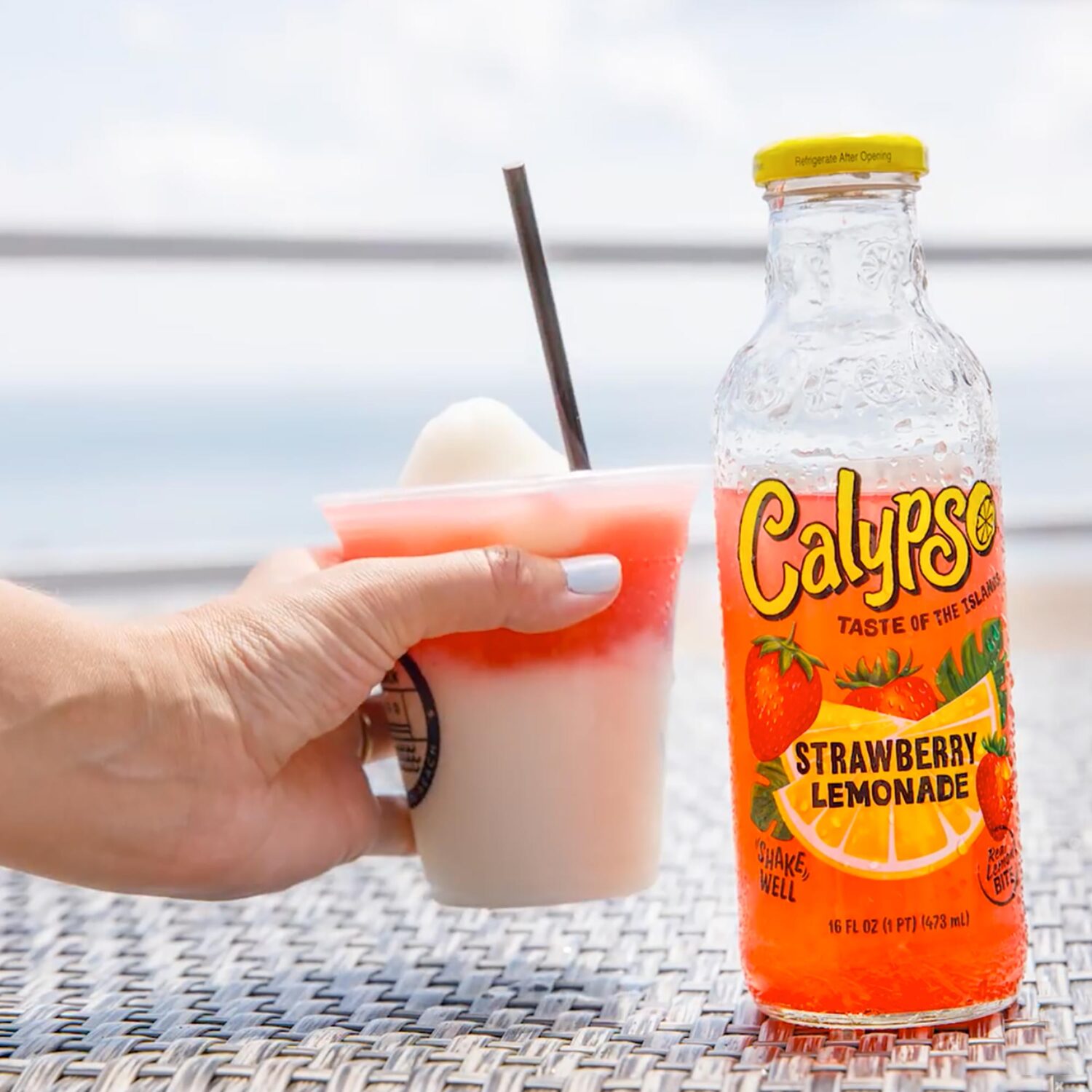 A person holding a frozen cocktail next to a bottle of Calypso Strawberry Lemonade.