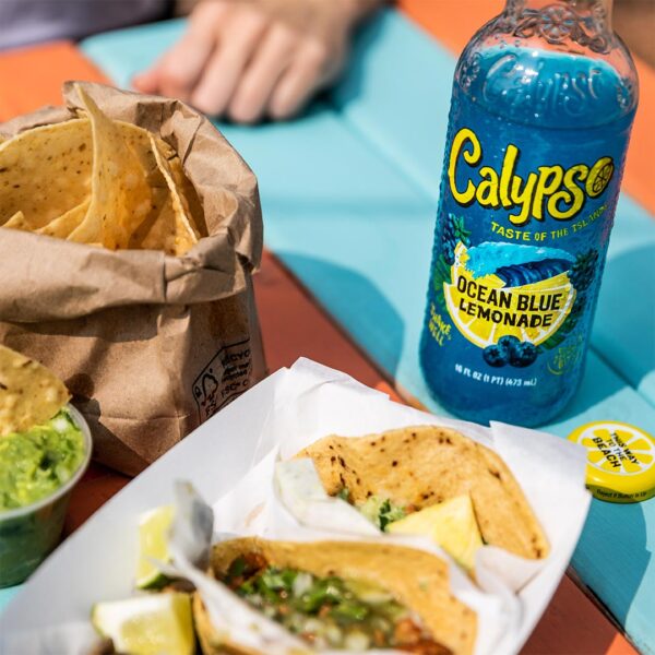 Calypso Ocean Blue Lemonade on a table with tacos, tortilla chips, and guacamole.