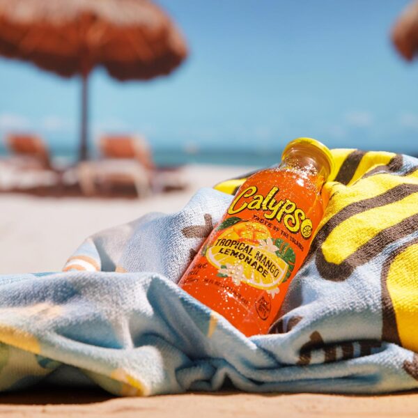 Calypso Tropical Mango Lemonade laying on a towel on the beach.